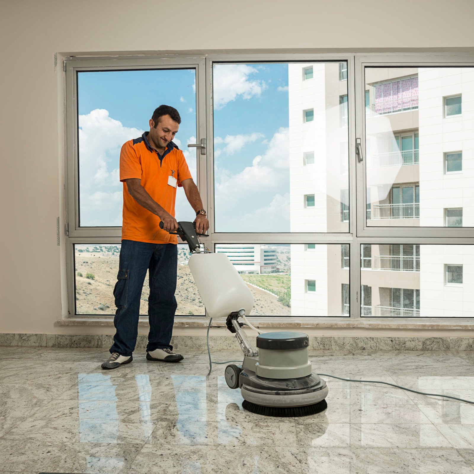Manual worker cleaning the floor with buffer machine.